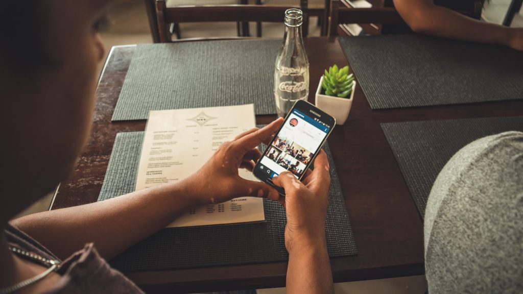 A person holding an iPhone, surfing through instagram